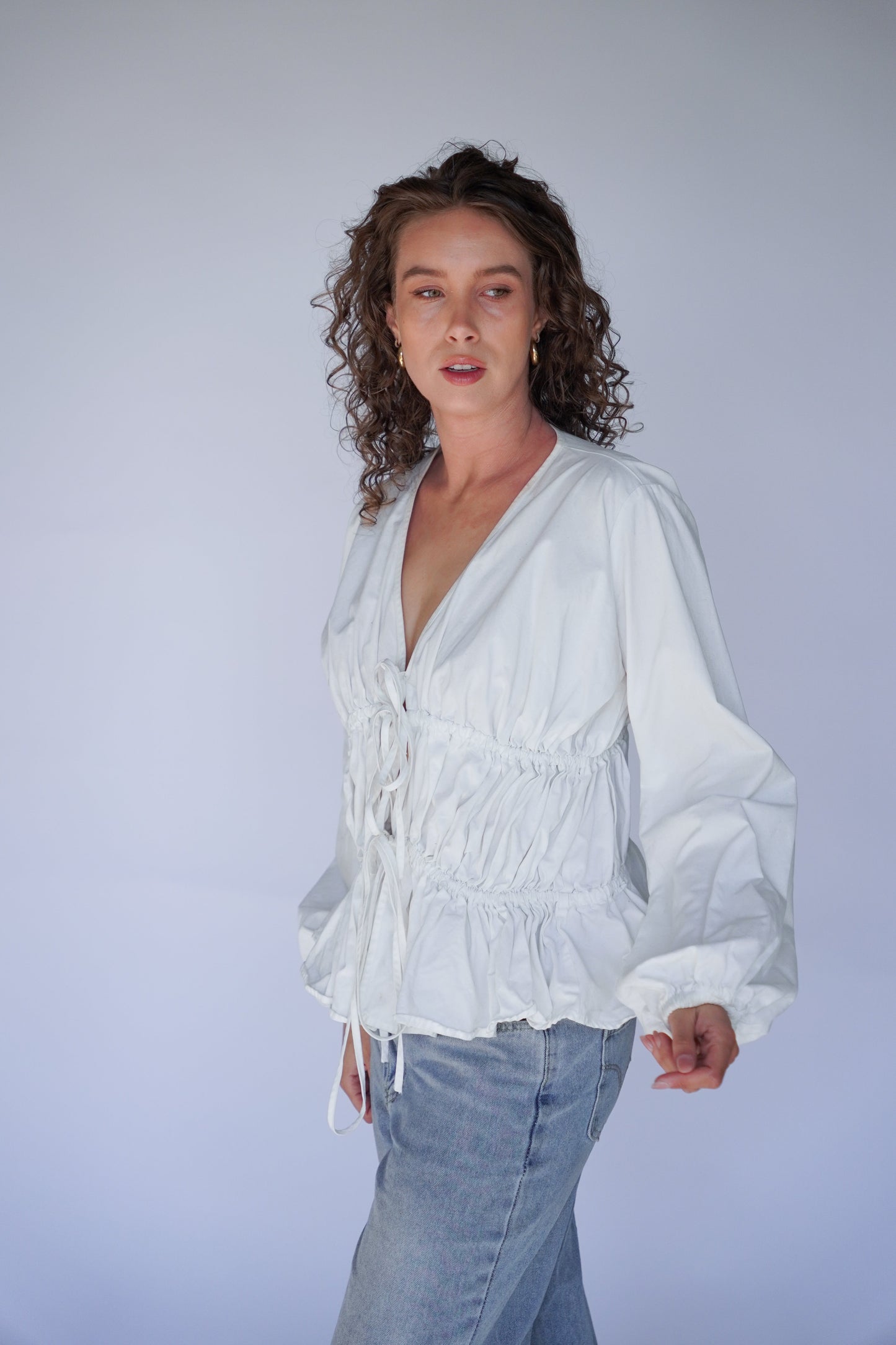 Person wearing a white blouse with a plain background