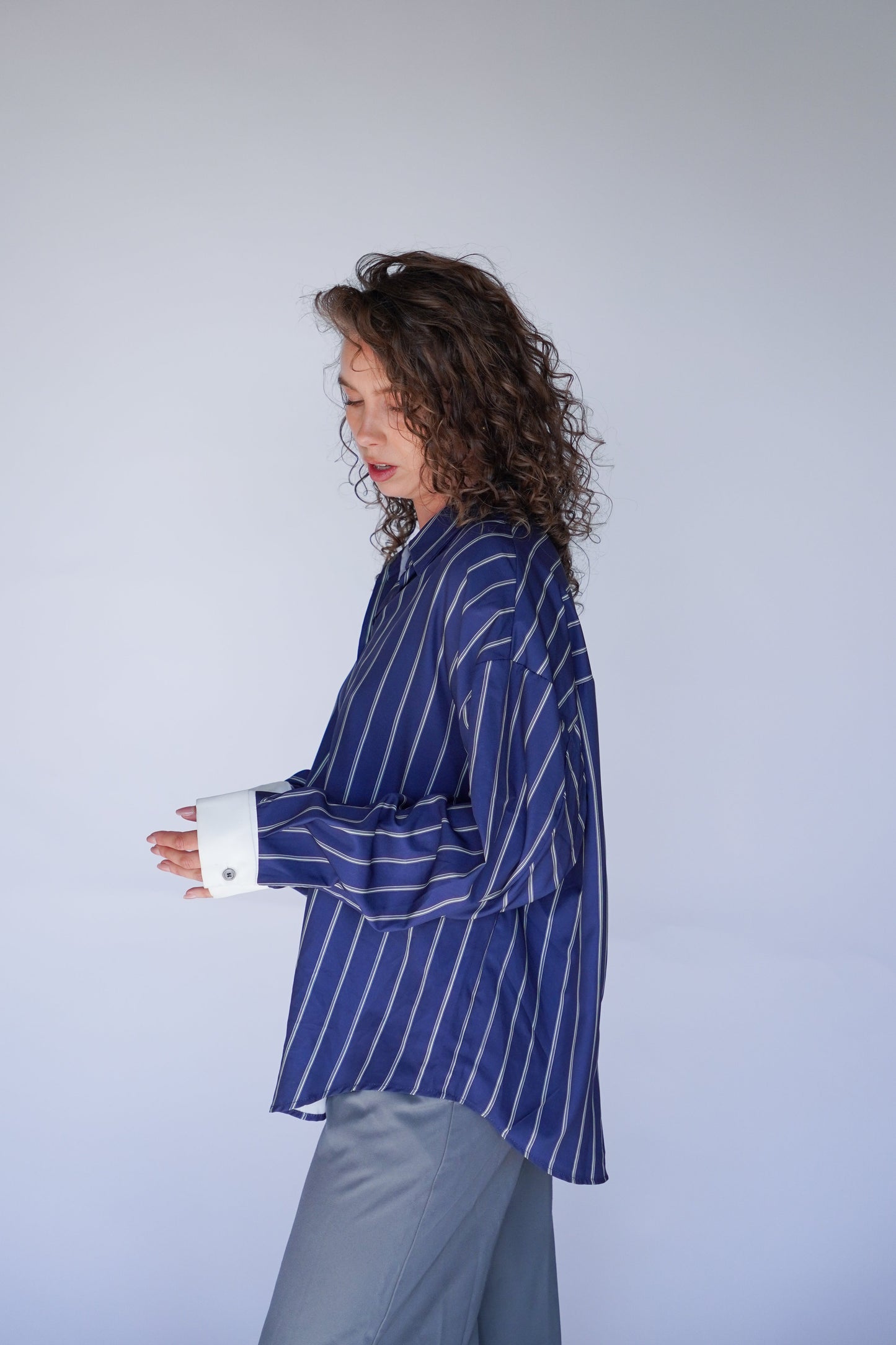 Person wearing a blue striped shirt and gray pants against a white background