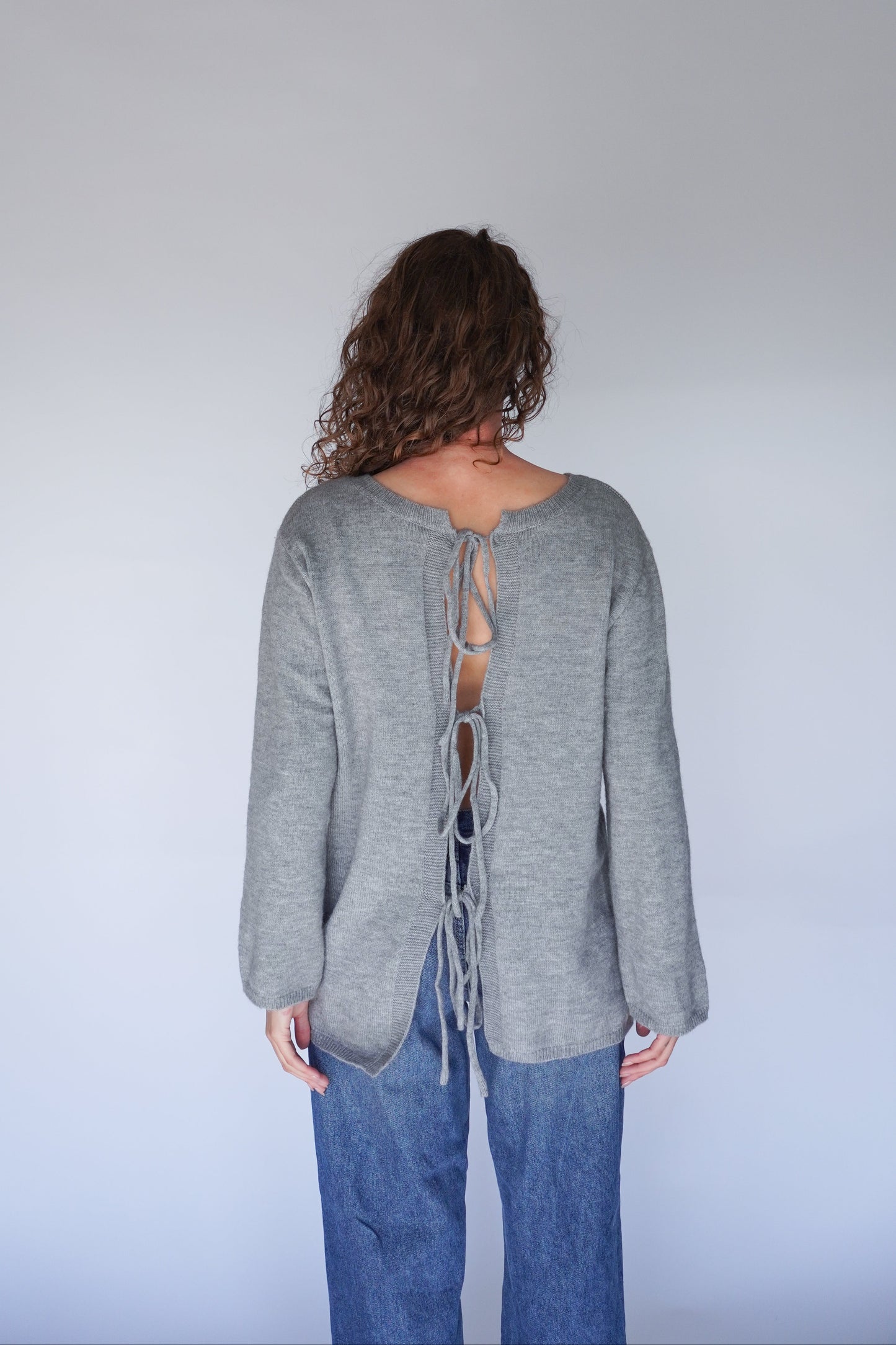 Person wearing a gray sweater with a lace-up back.