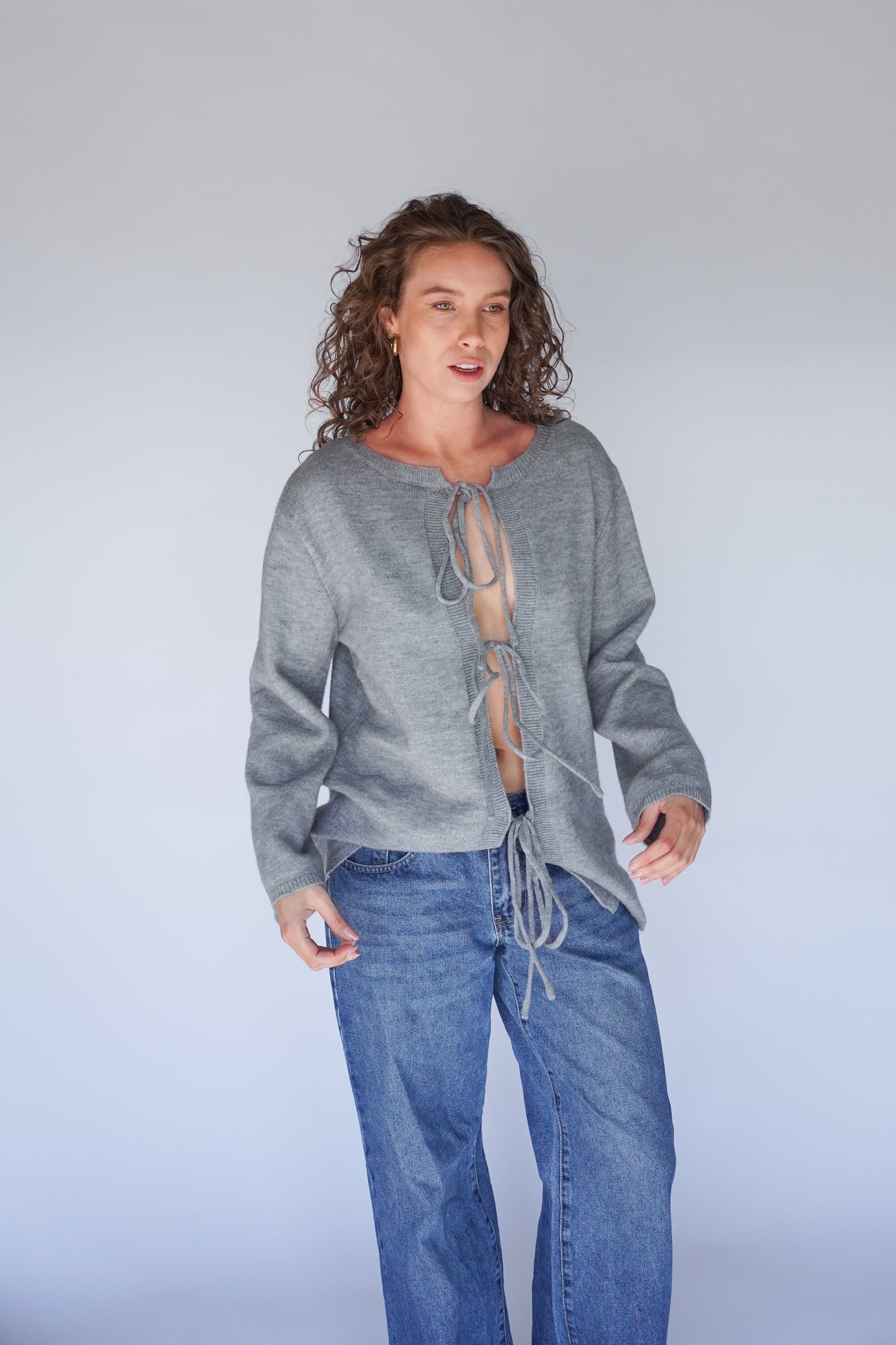 Person wearing a gray sweater and blue jeans against a plain background