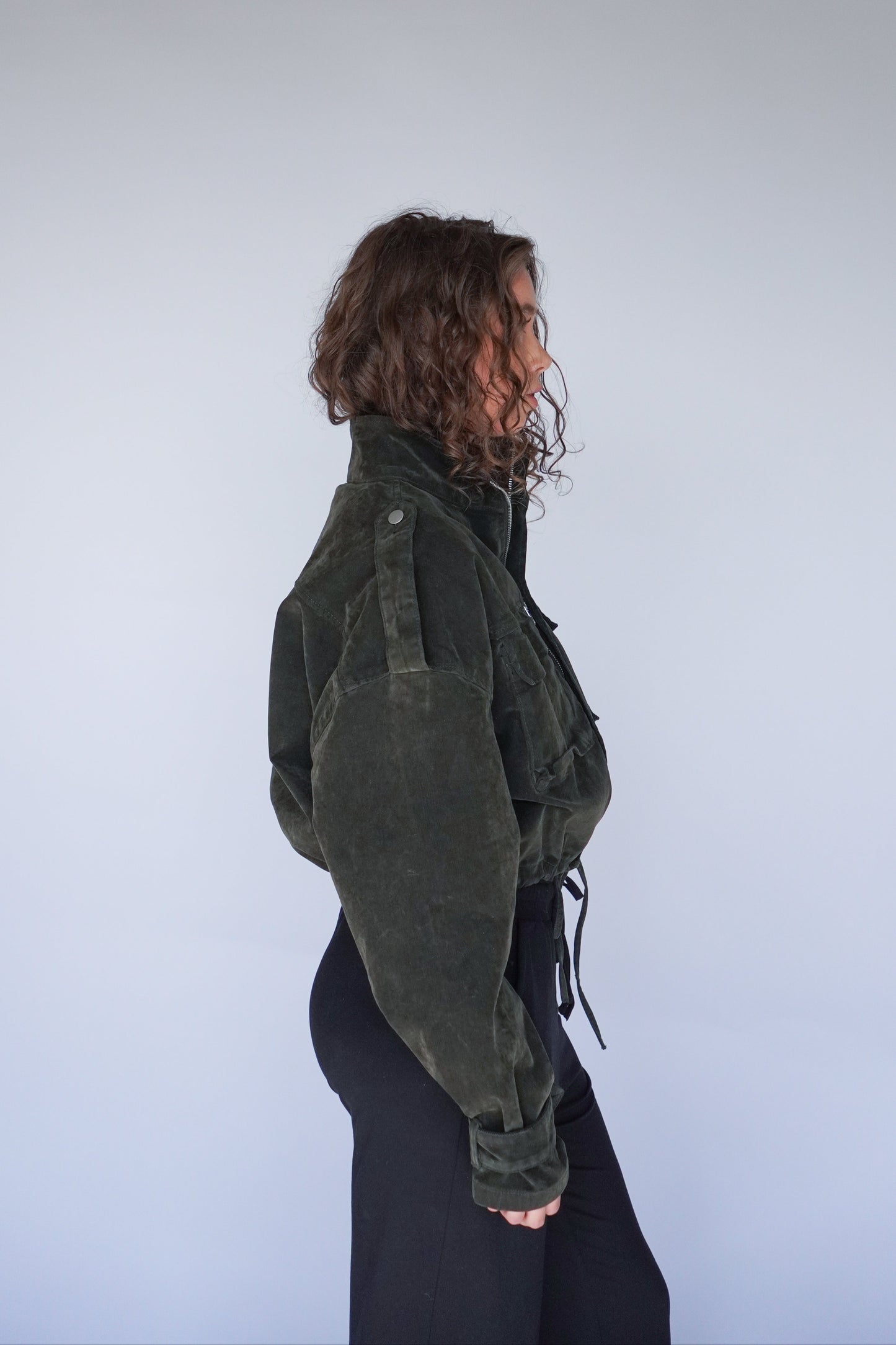 Person wearing a dark green jacket against a plain background