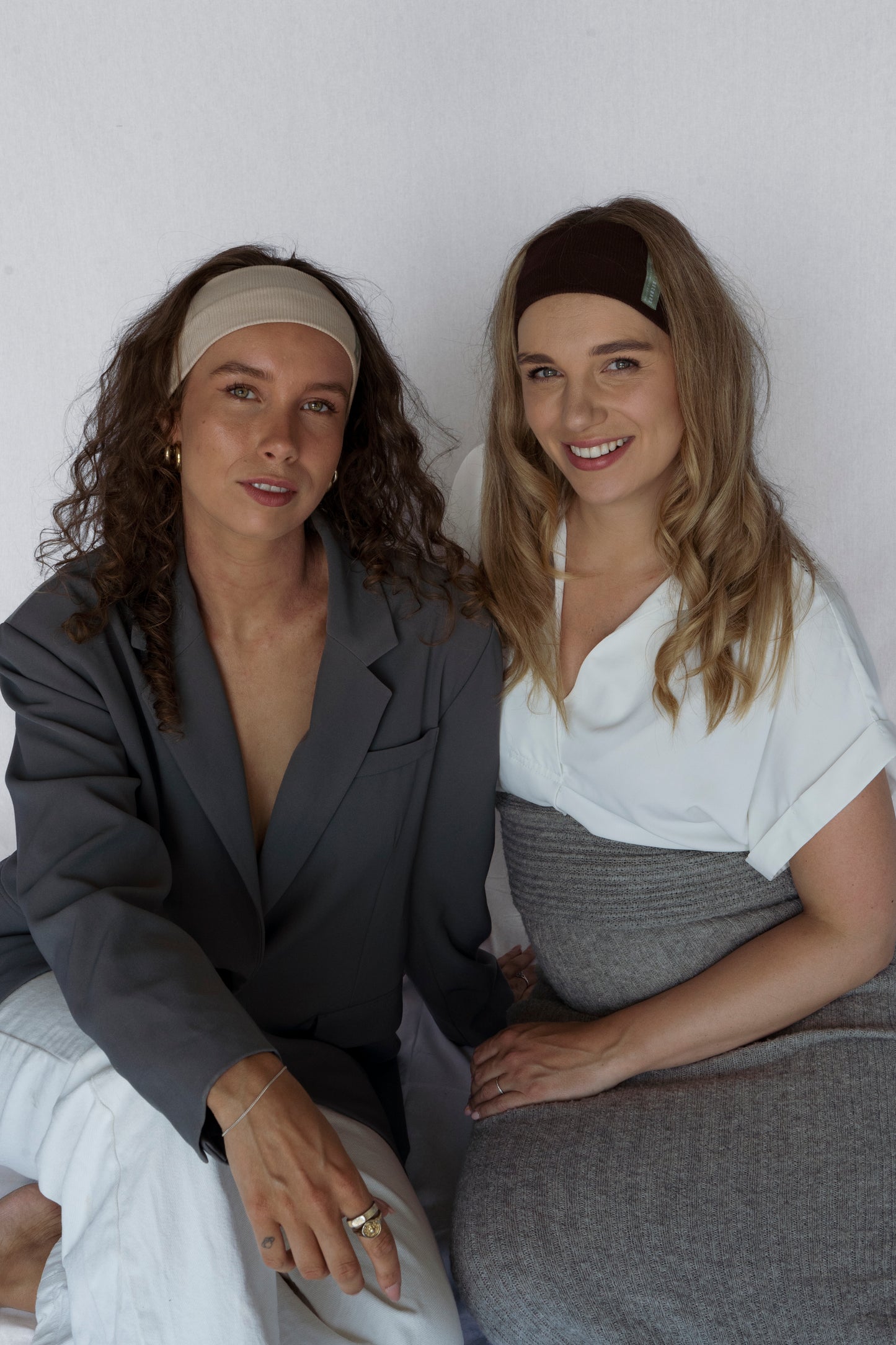 Two women sitting together against a white background