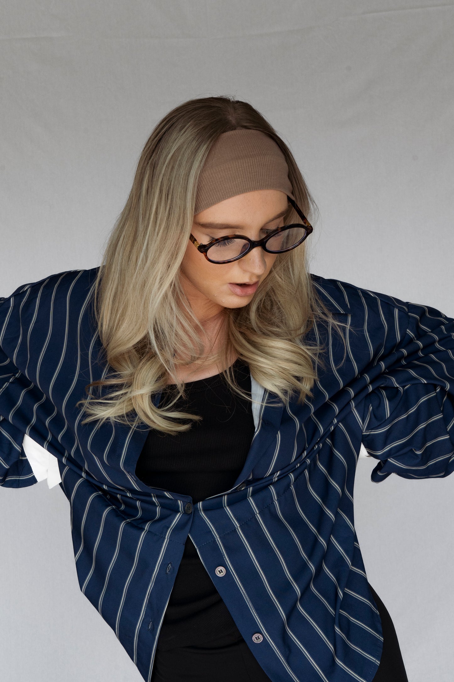Person wearing a blue striped blazer over a black top against a plain background