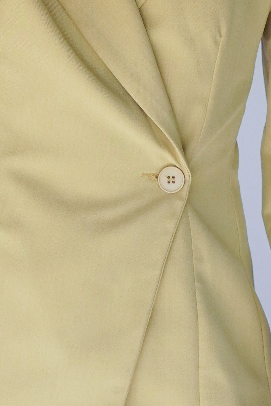 Close-up of a yellow garment with a button.
