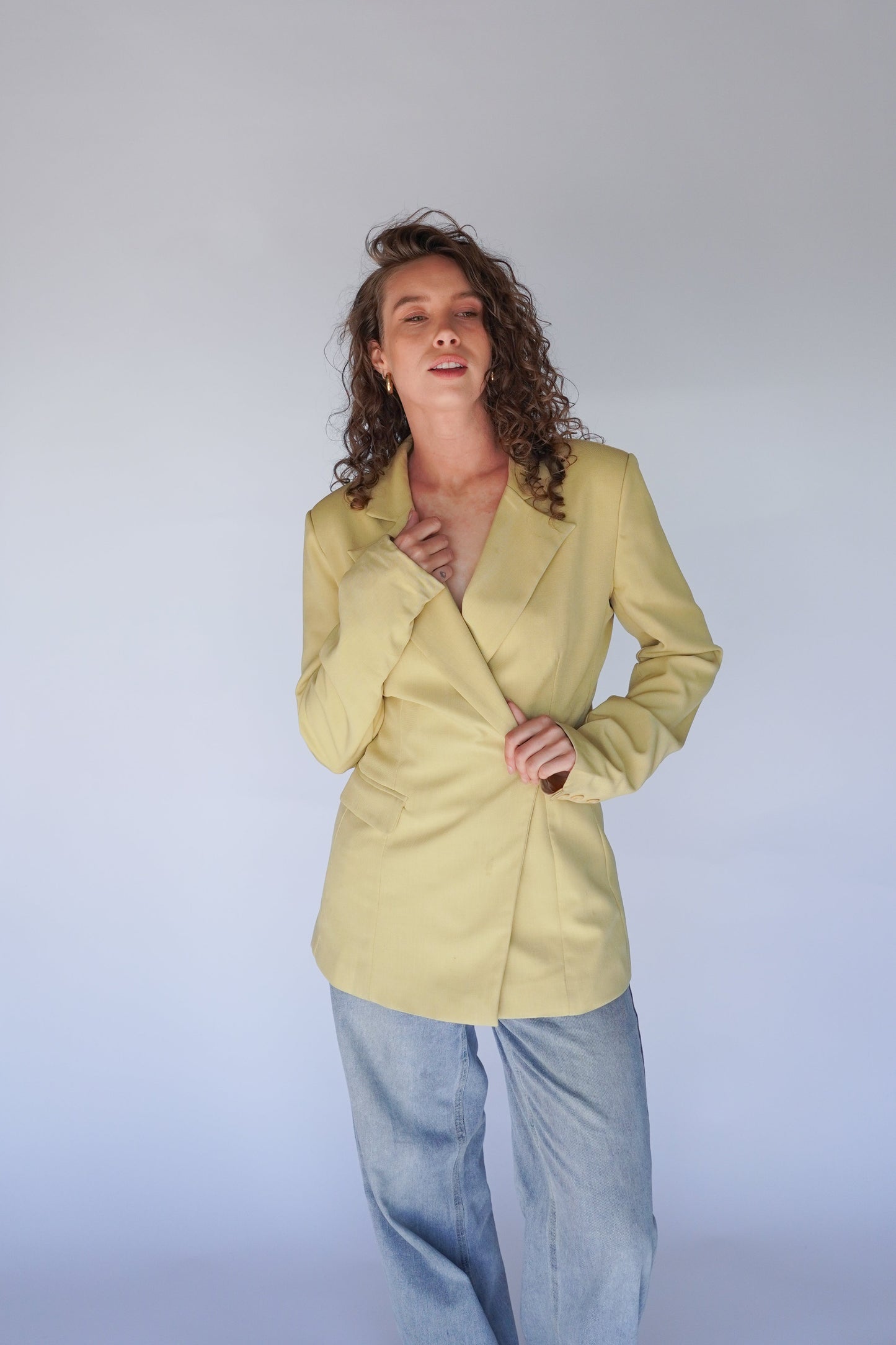 Person wearing a light yellow blazer against a plain background