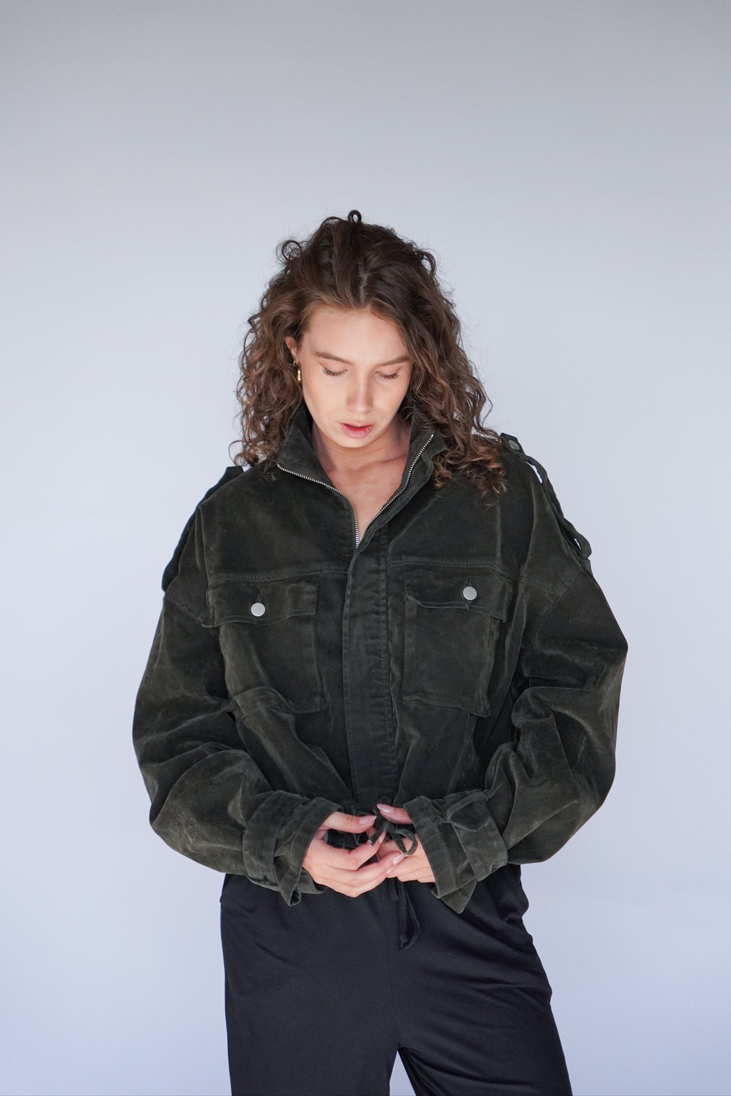 Person wearing a dark green jacket against a plain background