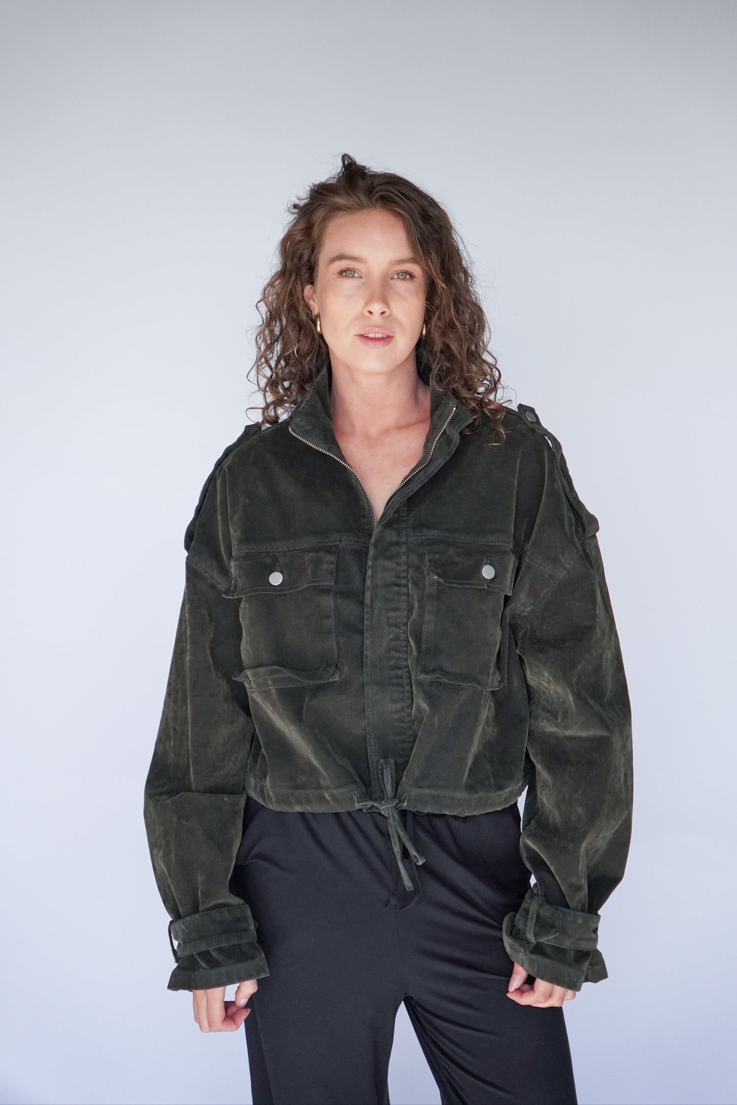 Person wearing a dark green jacket against a plain background