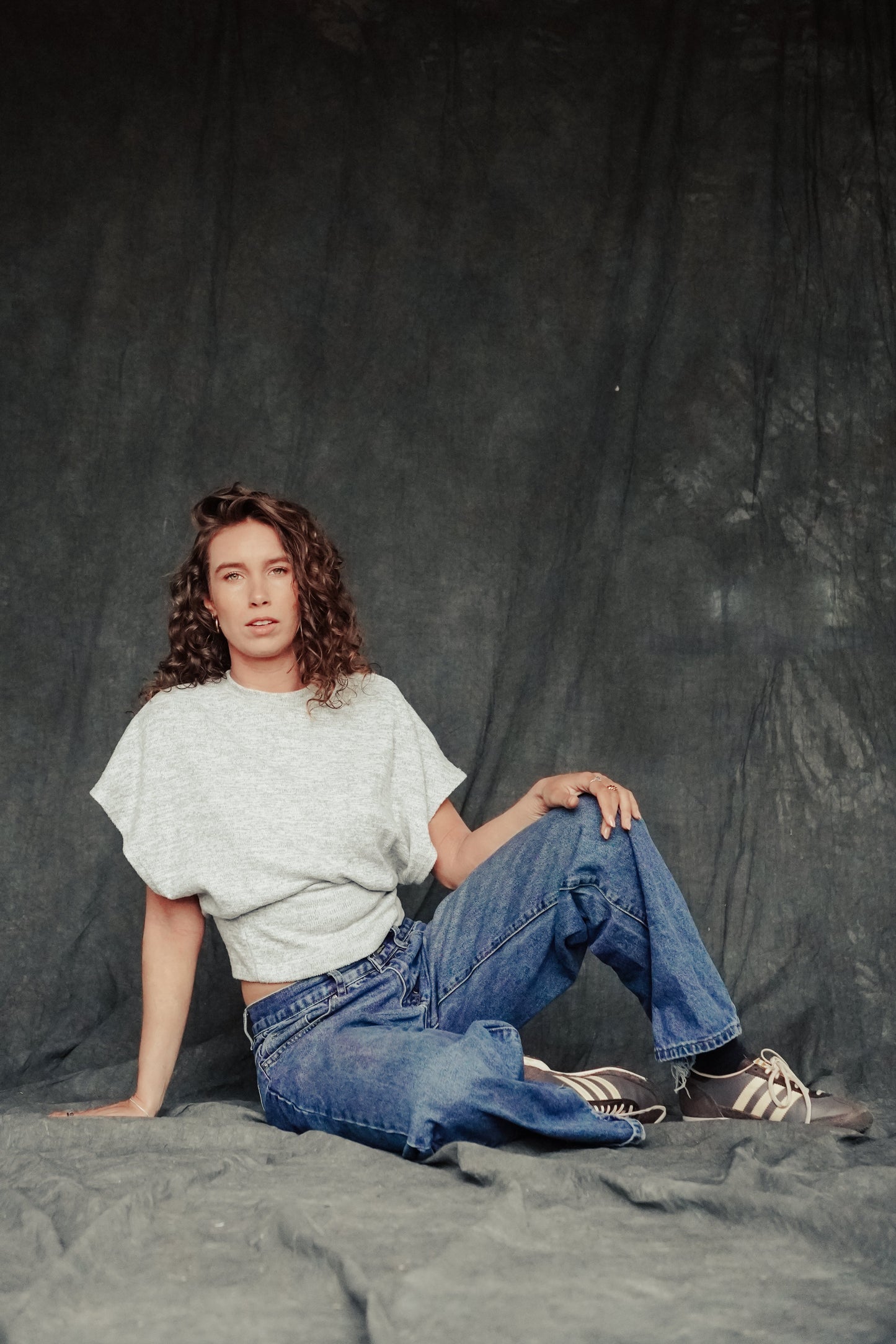 Person sitting on the ground against a dark background
